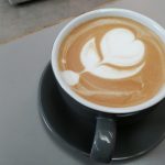 Top down view of a cup of coffee with a flower milk pattern