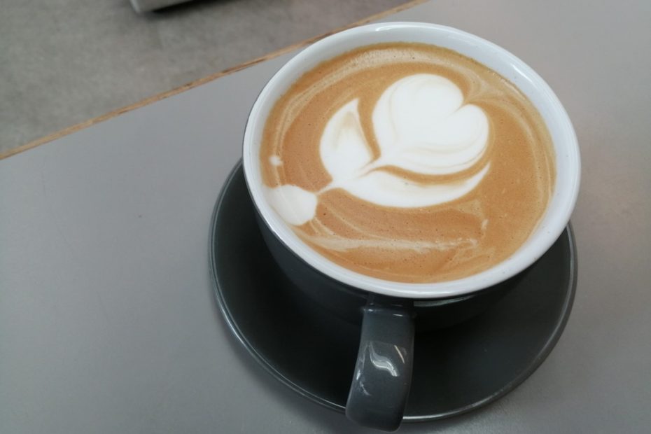 Top down view of a cup of coffee with a flower milk pattern