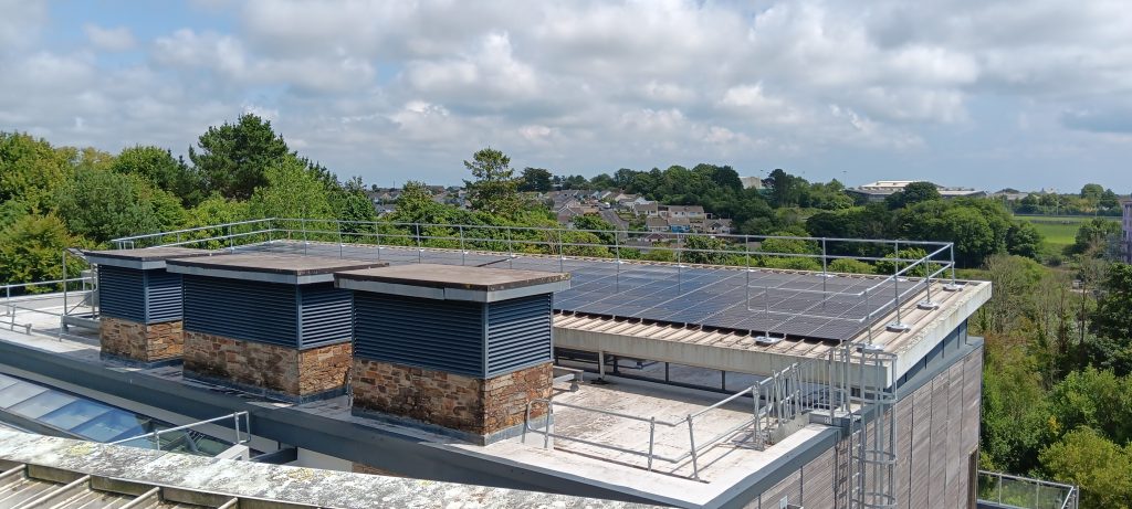 Image of the new PV panels on the roof of the AMATA building, looking out across the treetops towards Penryn.