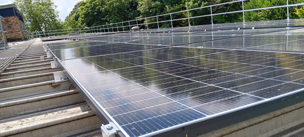 A close up image of the PV panels on the roof of AMATA with the reflection of the trees on the glossy, black solar panels. 