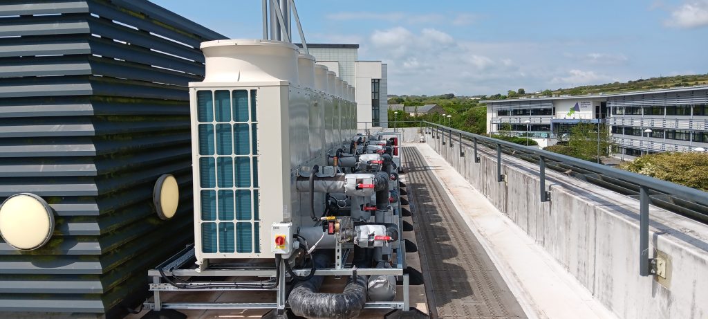 Another photograph of the four air source heat pumps on the roof of the Stella Turk building, but taken from a different angle looking out across Penryn campus.