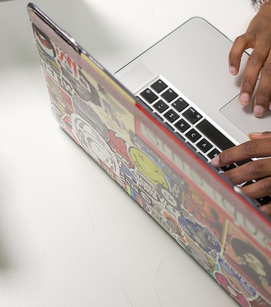 Image of the back of a laptop and someone using it.